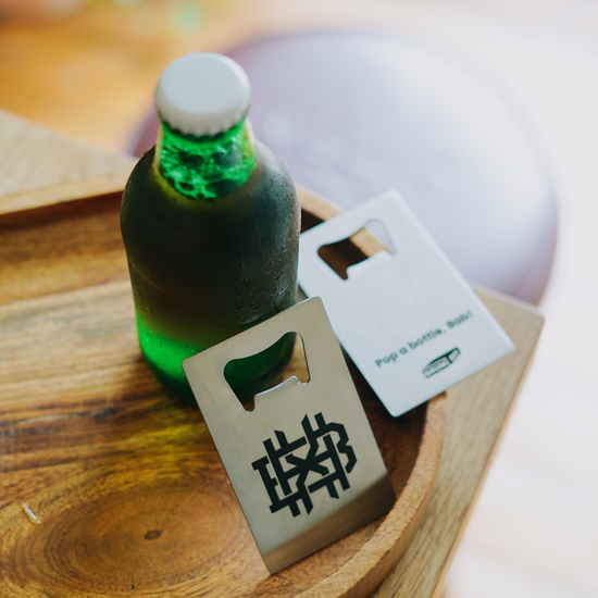 Brumbox BHX Monogram engraved credit card sized stainless steel bottle opener leant against glass bottle