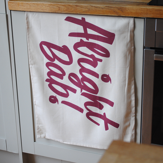 Brumbox Alright Bab cotton kitchen tea towel hanging off kitchen draw