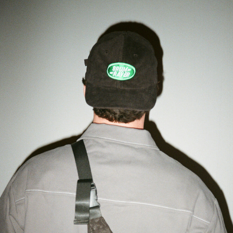 Model wears Brumbox's Brum Raver green and black cord cap