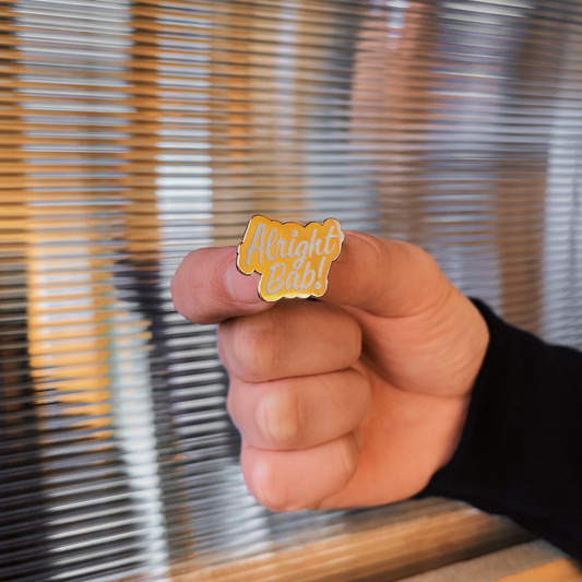 Brumbox gold coloured Alright Bab! enamel pin badge with white lettering.